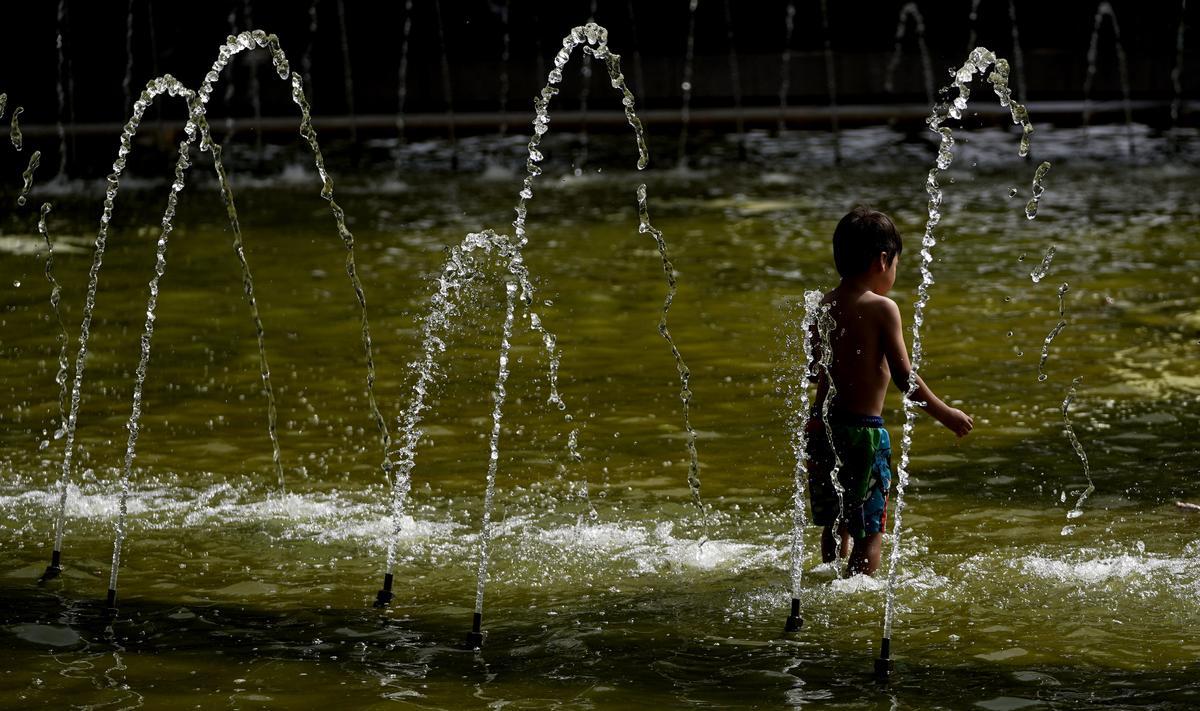 Un niño se refresca en una fuente durante la ola de calor.