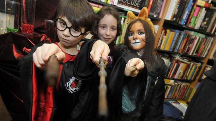 Tres niños a punto de pronunciar un hechizo ayudados por sus varitas mágicas.