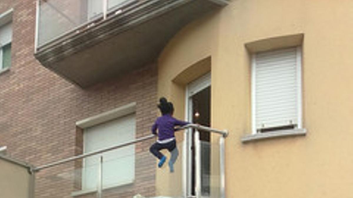 Una niña encaramada a un balcón en Vic