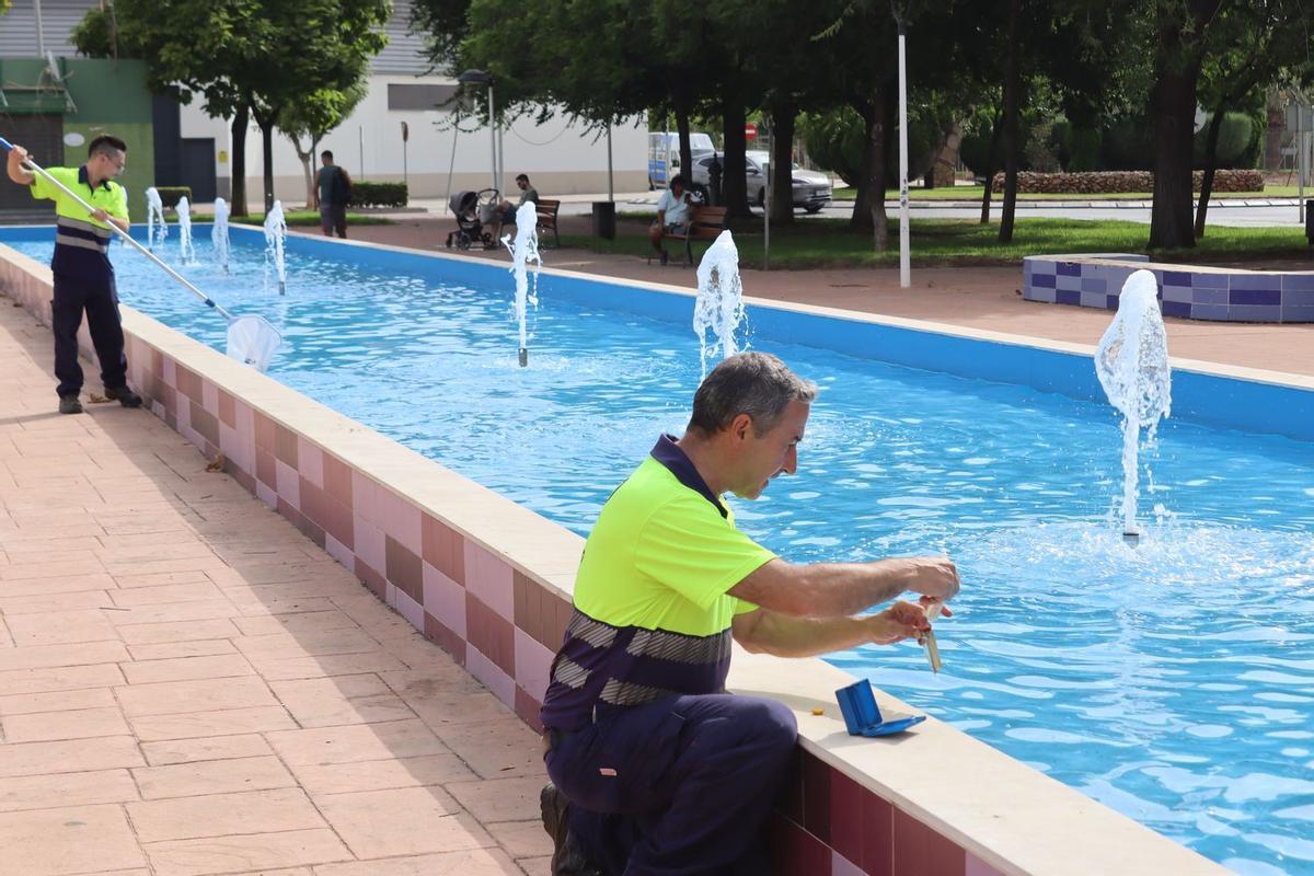 Dos operarios limpian la fuente de la Mayorazga de Vila-real y comprueban los niveles de cloro y ph del agua de la misma.