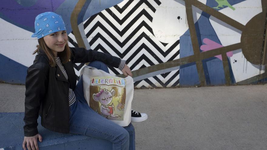 Olivia Jakóbiec, davant el mural del Parc Bosc, amb una bossa amb el logotip del canal Literatita.