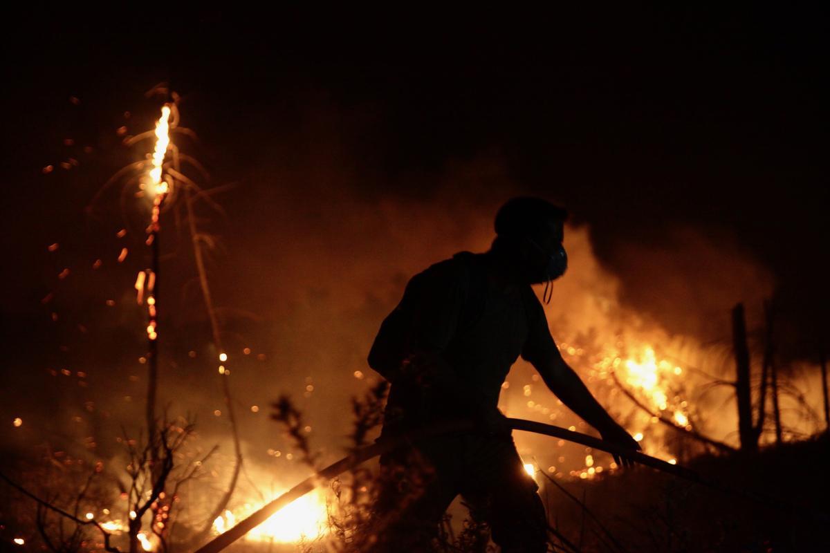 Un bombero participa en las tareas de extinción del incendio en la localidad de Asklipio.