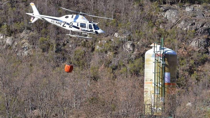 Un helicóptero procede a recoger agua, junto a un silo de sal, para sofocar un incendio en Sanabria.