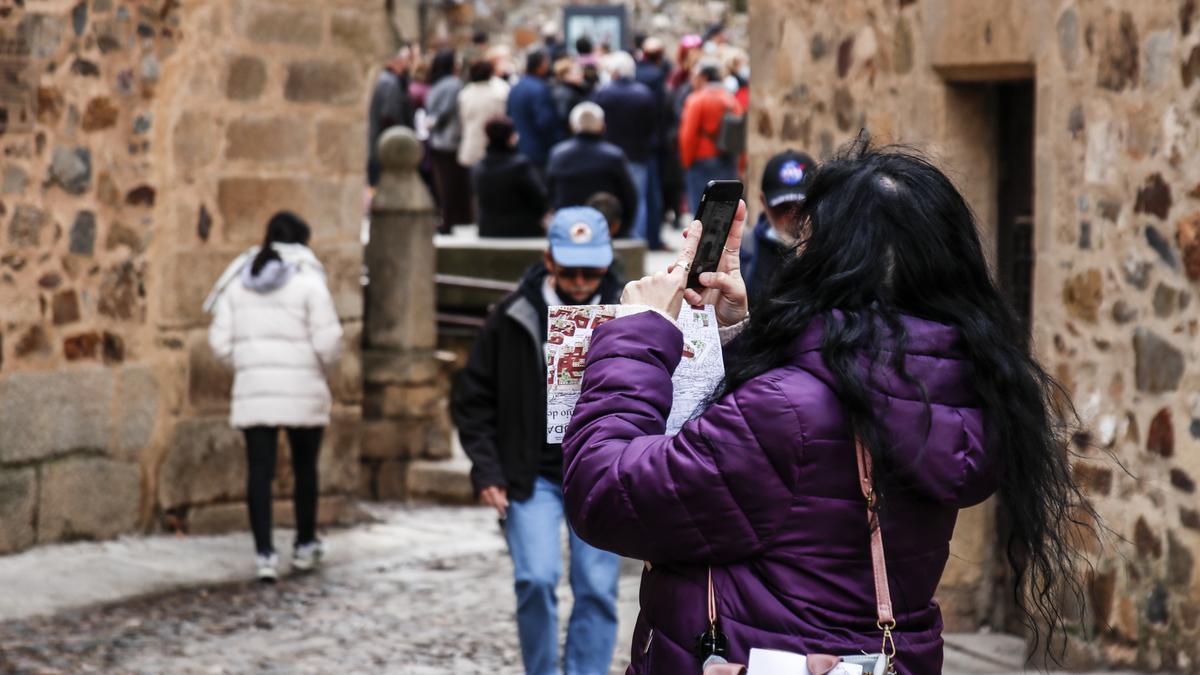 Una turista realiza fotografías con su &#039;smartphone&#039; frente al Palacio de los Golfines de Abajo, en Cáceres.