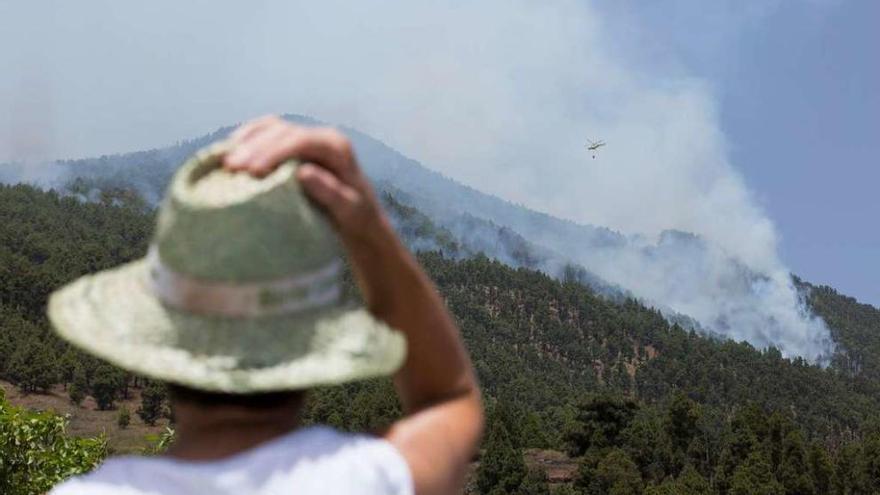 Un residente observa cómo un helicóptero arroja agua sobre el fuego.