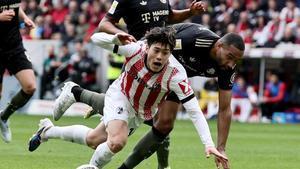 Yuito Suzuki, del Friburgo, cae ante Jonathan Tah en el último partido de la Bundesliga contra el Bayern.