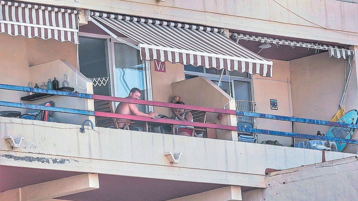 Una pareja disfruta de la terraza de una vivienda vacacional, con el cartel de ‘Vv’, en el sur de Tenerife.