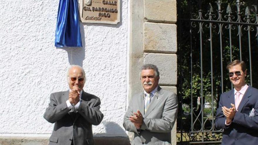 Gil Parrondo, a la izquierda, agradece los aplausos tras el descubrimiento de la placa de la calle que lleva su nombre, junto al alcalde de Valdés, José Modesto Vallejo, y el concejal de Cultura, Juan Guisasola.