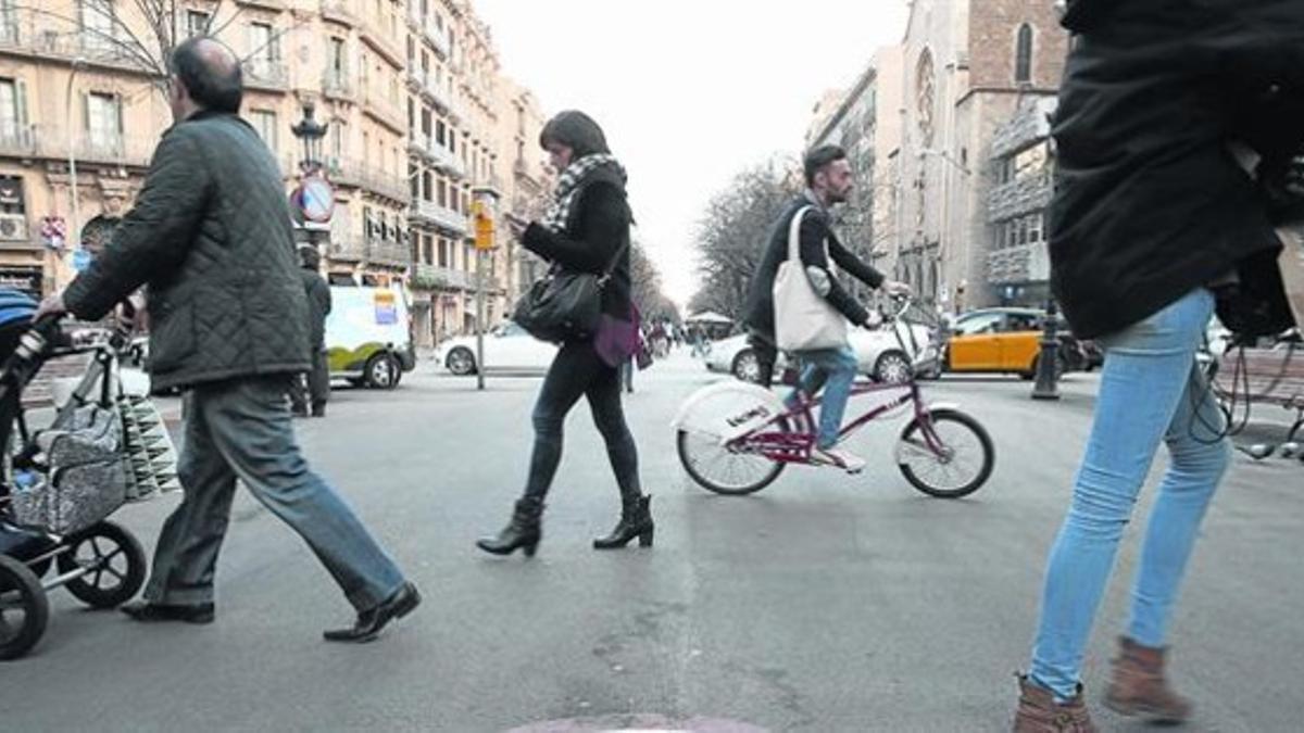 Un ciclista circula entre peatones por una acera del Eixample, en junio del año pasado.