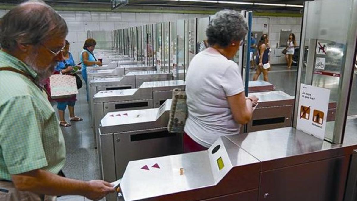 Varios usuarios validan sus billetes en las máquinas de la estación de metro de Plaça Universitat, en Barcelona, ayer.
