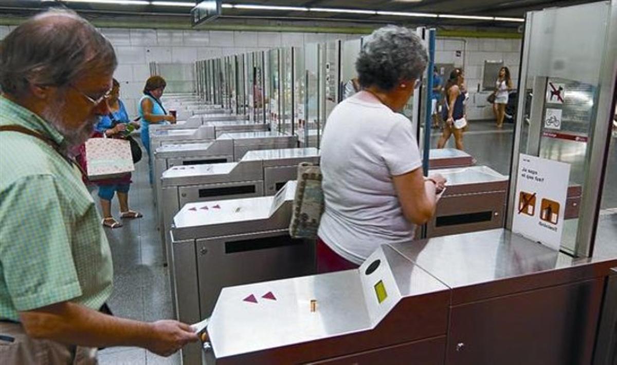 Varios usuarios validan sus billetes en las máquinas de la estación de metro de Plaça Universitat, en Barcelona, ayer.