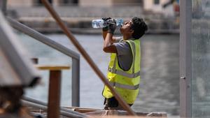 Un obrero que trabaja en la rehabilitación del muelle del Maremàgnum de Barcelona bebe agua para paliar el calor, el pasado día 3.