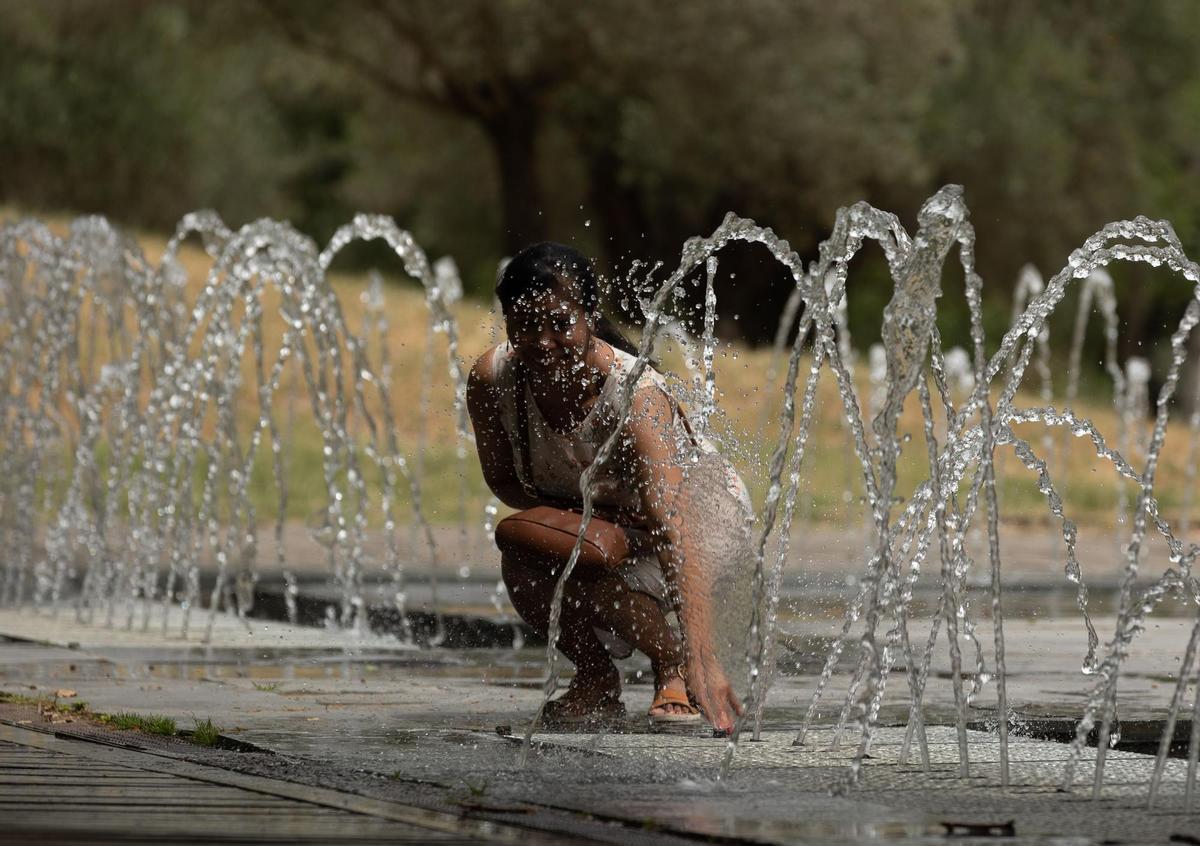 Una mujer se moja en los chorros de Madrid Río para aliviar la ola de calor.