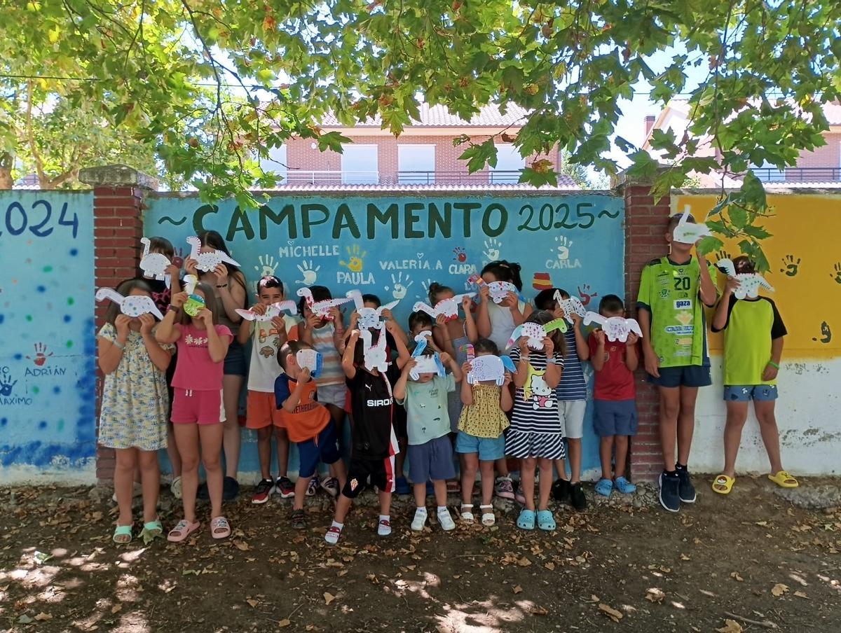 Los niños con sus manualidades en el mural del campamento