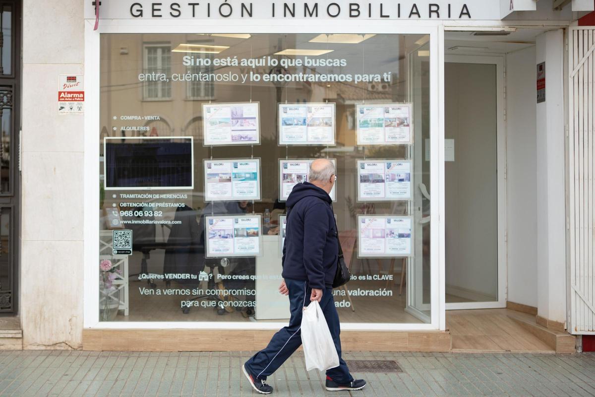 Un hombre pasa por delante de una inmobiliaria de Cartagena donde se anuncian viviendas a la venta.