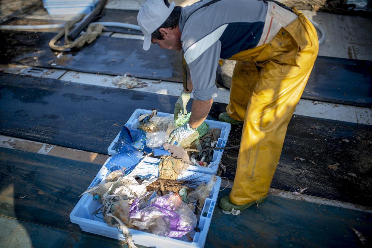 Un pescador depositando los restos de plástico extraidos del mar para su traslado a tierra.