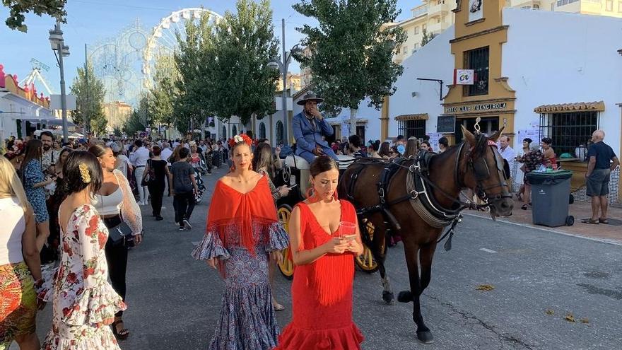 Varias mujeres vestidas de flamenca pasean por el recinto ferial de la Feria de Fuengirola.