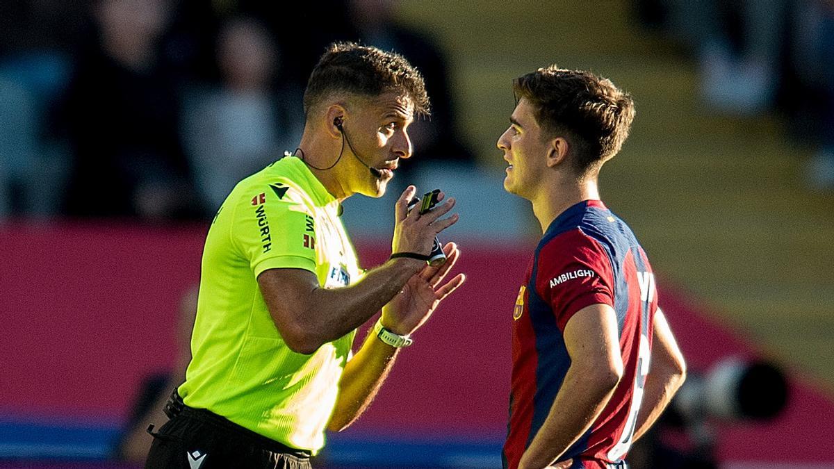 Gil Manzano, el colegiado extremeño, da instrucciones a Gavi en el clásico de Montjuïc.