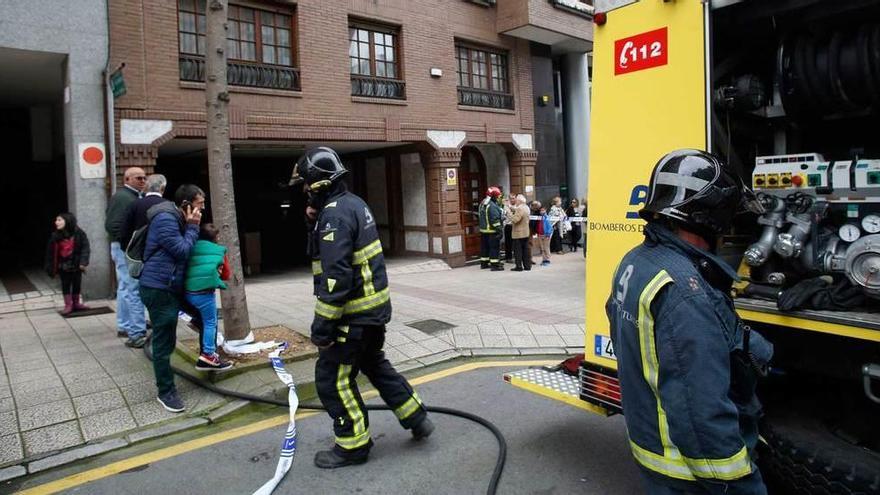 Bomberos y curiosos, ante el acceso al garaje de Severo Ochoa en el que se produjo el incendio.