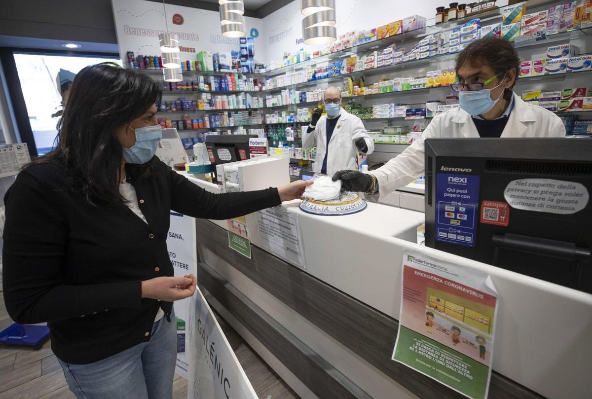 Rome (Italy), 09/04/2020.- A pharmacist hands a face mask to a customer, in Rome, Italy, 09 April 2020, during the coronavirus disease (COVID-19) pandemic. New provisions of face masks arrived to the pharmacies in the country to fight the coronavirus pandemic. (Italia, Roma) EFE/EPA/CLAUDIO PERI