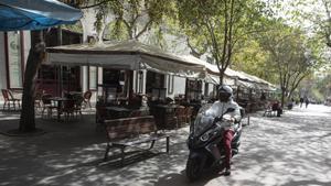 Una moto circula por la peatonal Enric Granados junto a una macroterraza, este miércoles.