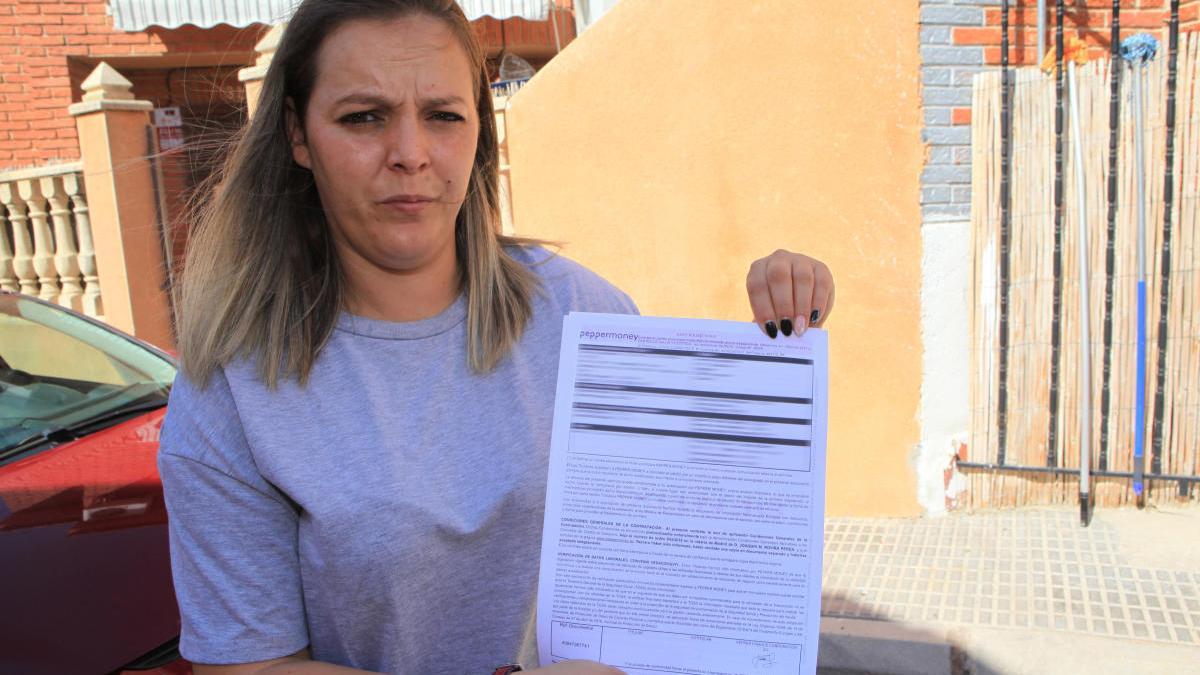 Manuela López, afectada por las estafas de iDental y Dentix, posa en Abanilla con el contrato la financiera de Dentix.