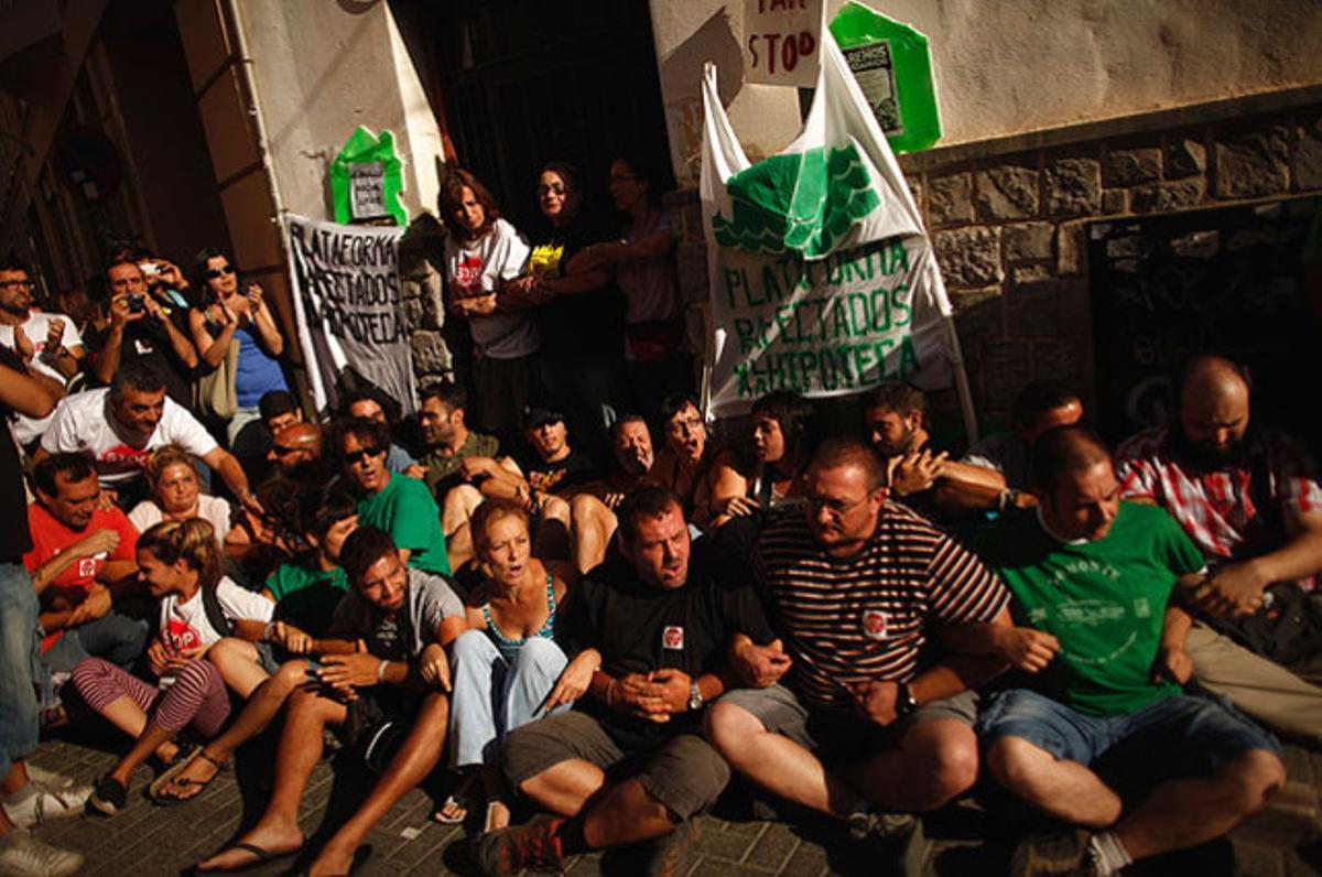 Membres de moviments Stop Desnonaments i PAH bloquegen la porta de la vivenda de Rebeca Heredia, a Màlaga, per evitar el seu desallotjament, ajornat fins a l’octubre.