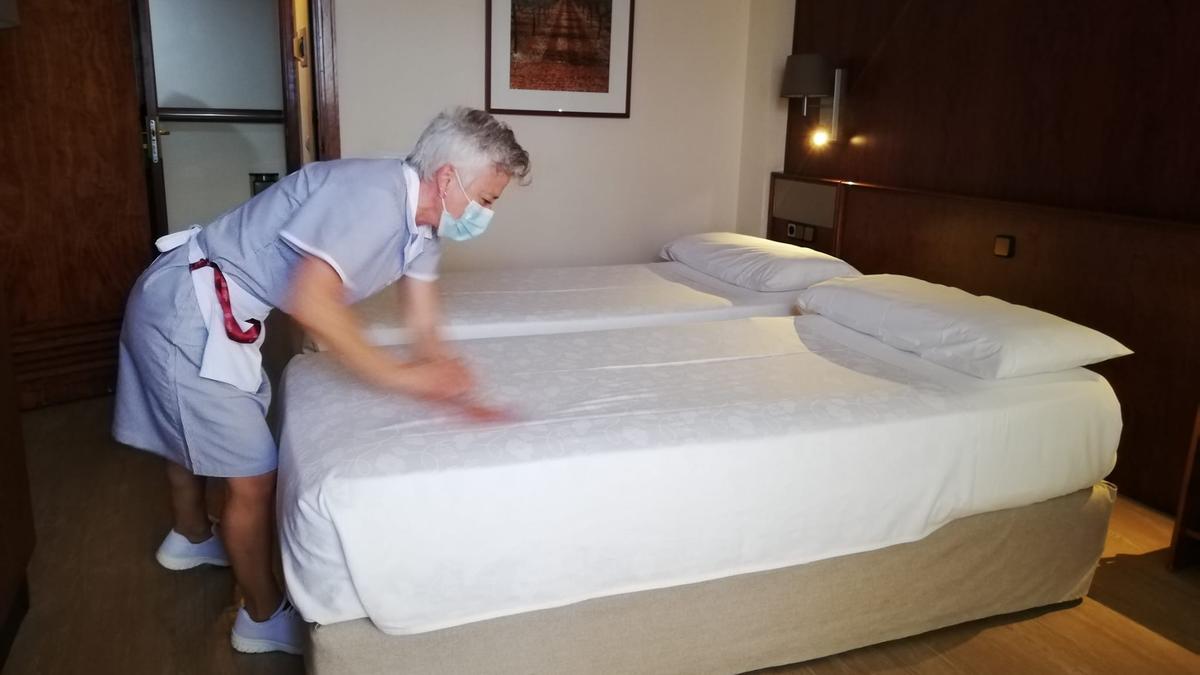 Una camarera de piso prepara una cama en un hotel de las islas.