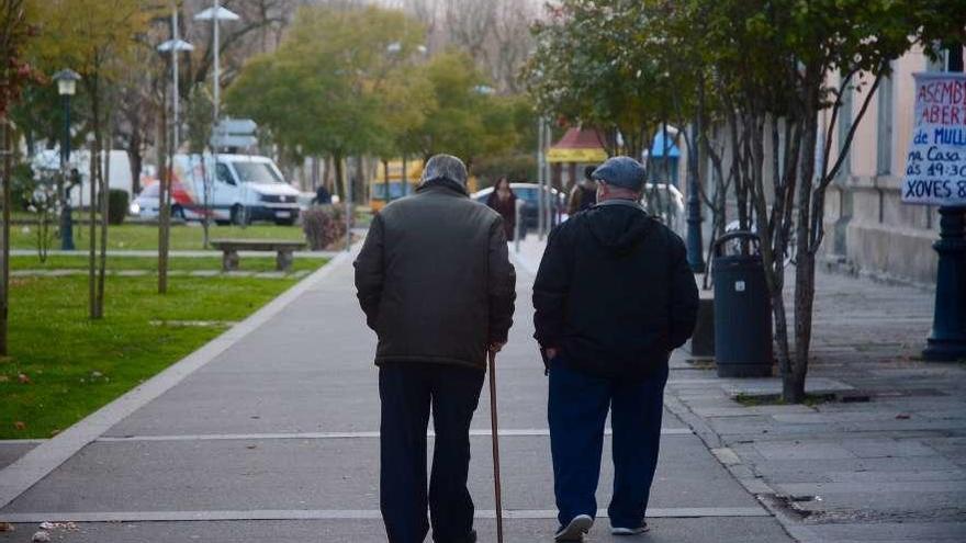 Dos personas mayores caminan por un paseo.