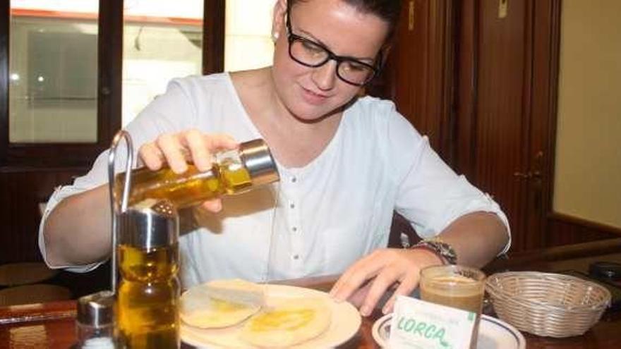 Una mujer desayuna mollete de Antequera con aceite.