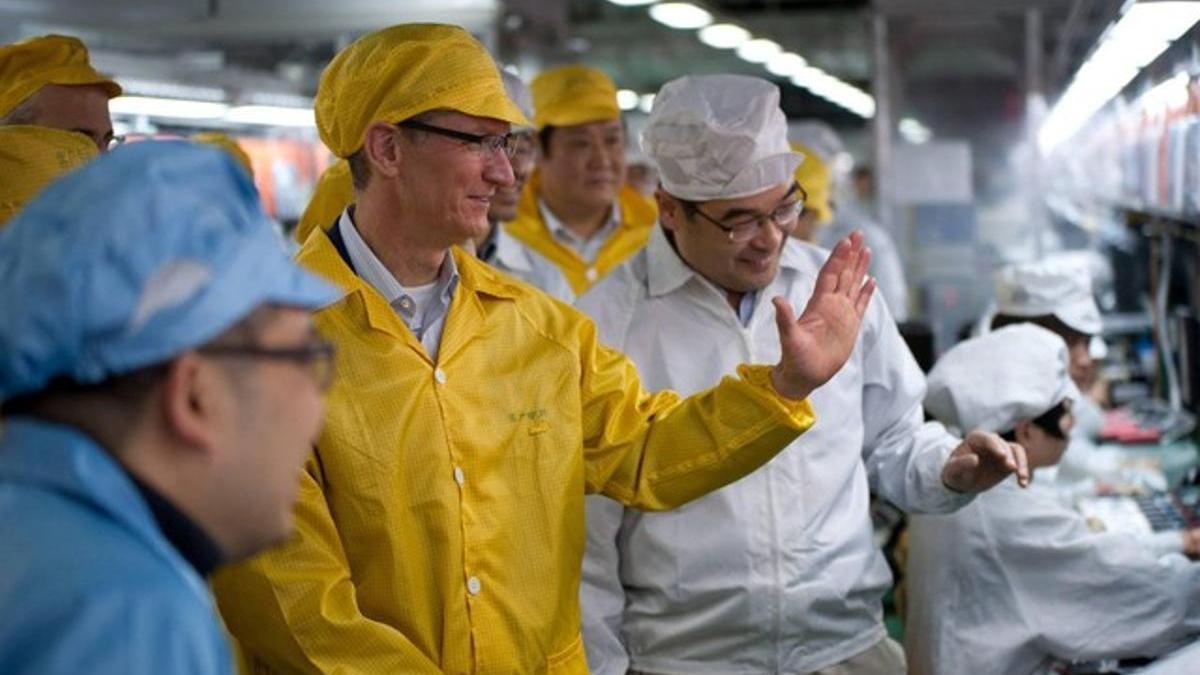 Tim Cook (en primer término, de amarillo), consejero delegado de Apple, durante una visita a una factoría de Foxconn en Henan (China), el pasado marzo.