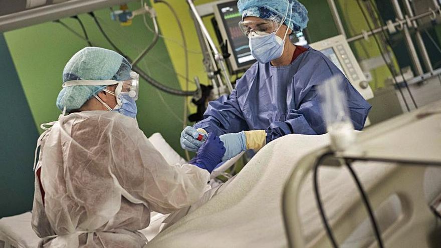 Dos sanitarias atienden a un paciente en una UCI.  | GERMÁN CABALLERO