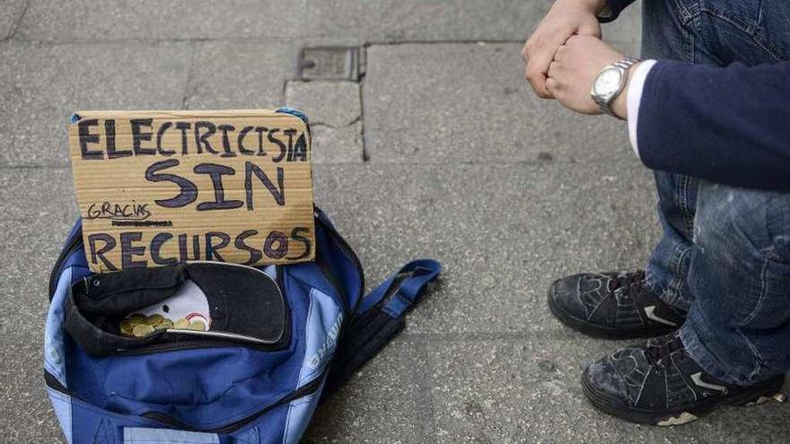 Un hombre pide ayuda en la calle con un cartel.