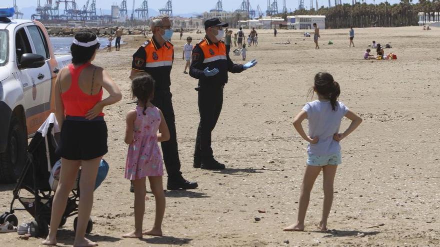 Miembros de Protección Civil junto a varias personas en la playa de Patacona, en Aboraya (Valencia).