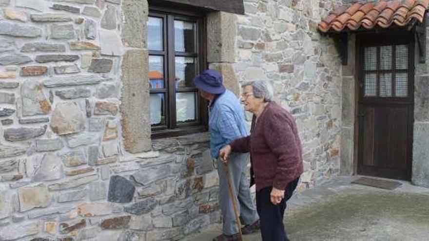 Dos vecinos, junto a una de las viviendas asaltadas en Oviñana.