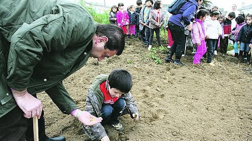 Santiago Jarén, a la izquierda, enseña a un niño a plantar maíz.