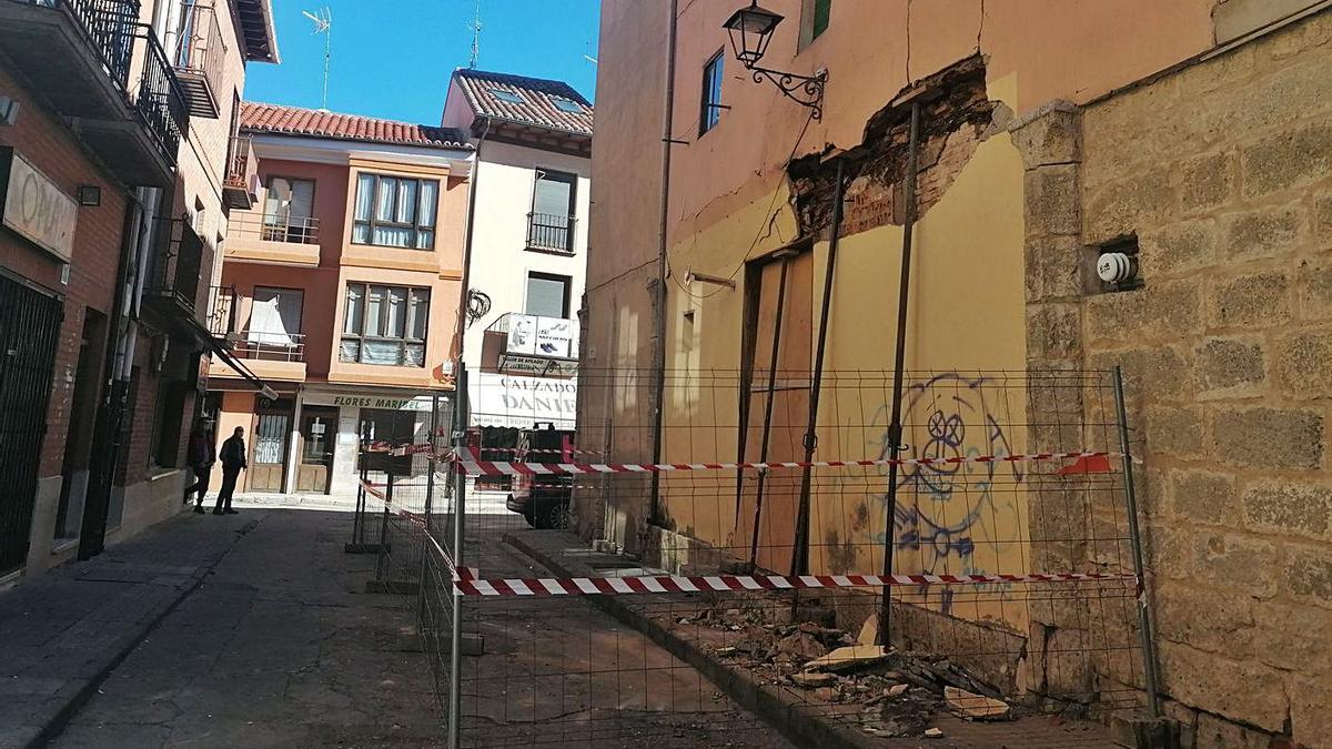 Dos vecinos observan desde la distancia el muro del edificio en el que ha sido apuntalada una viga. | M. J. C.