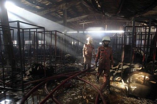 Firefighters inspect a burnt garment factory after a fire, in Gazipur