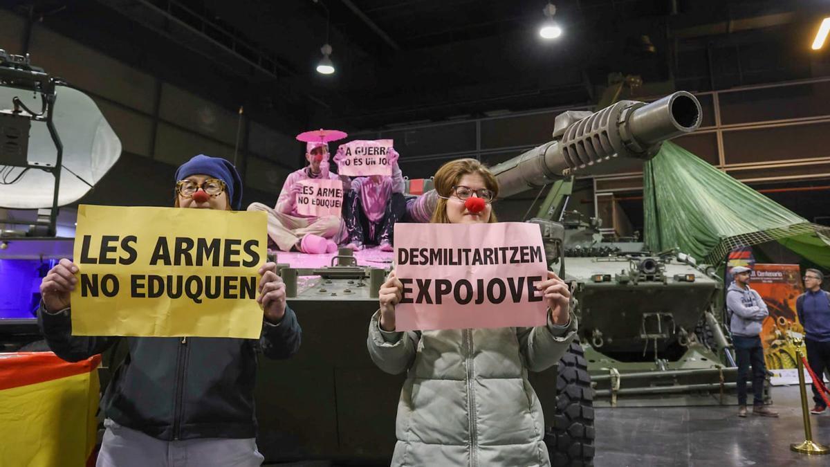 Dues persones pinten de rosa un tanc a Expojove en protesta per la militarització de la fira