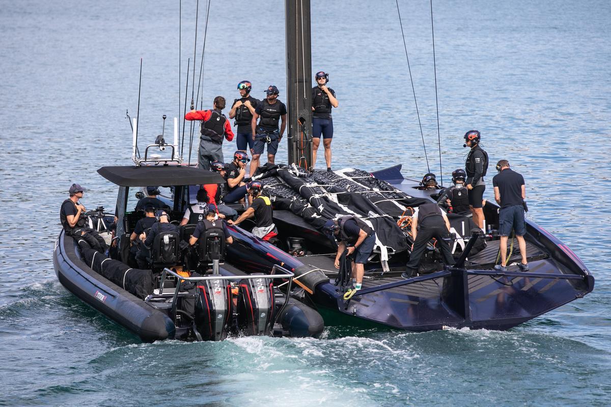 El monocasco AC75 del equipo Alinghi Red Bull Racing de la Copa América de vela sale del Port Vell arrastrado por otra embarcación para ir a entrenar, en junio de 2023.