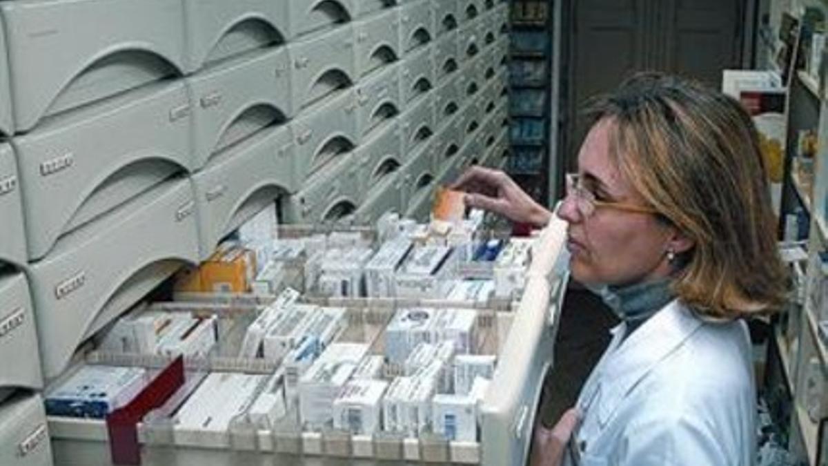 Una farmacéutica busca un medicamento en un cajón.