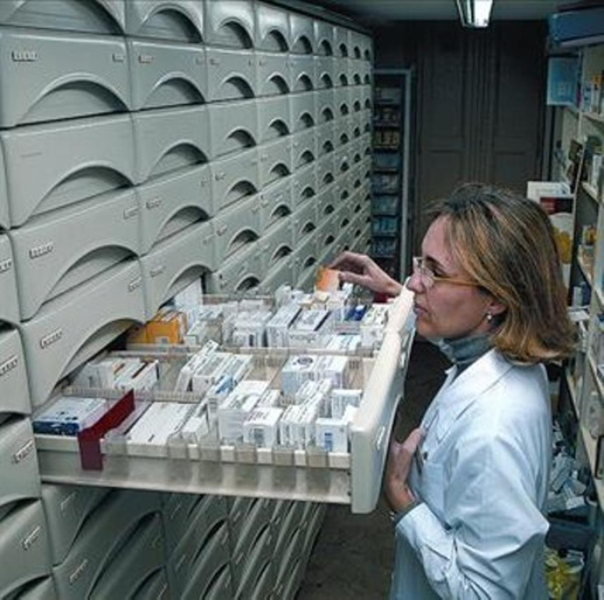 Una farmacéutica busca un medicamento en un cajón.
