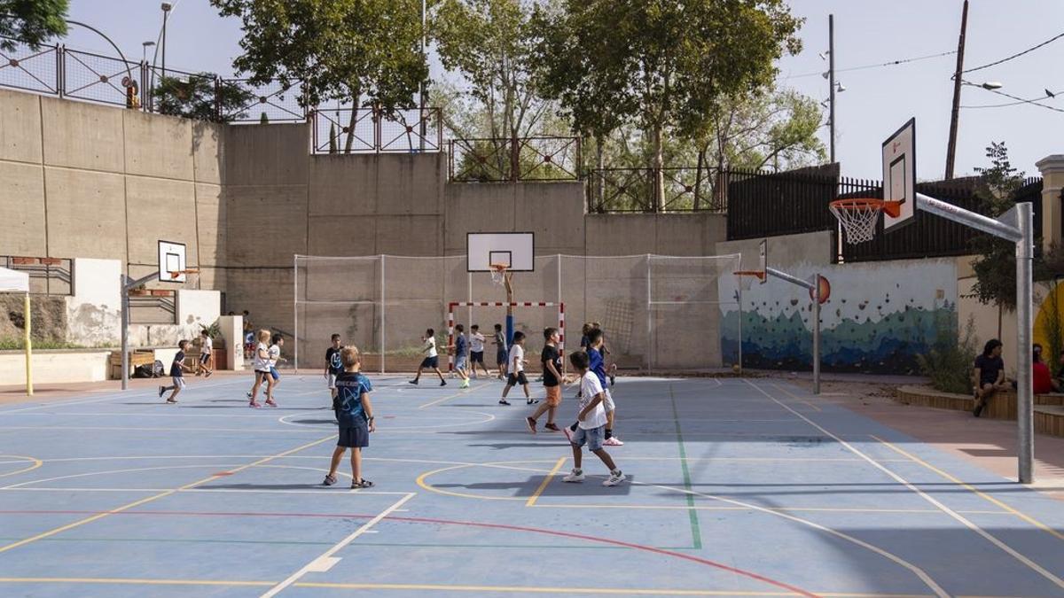 Niños jugando a fútbol en un patio de escuela.