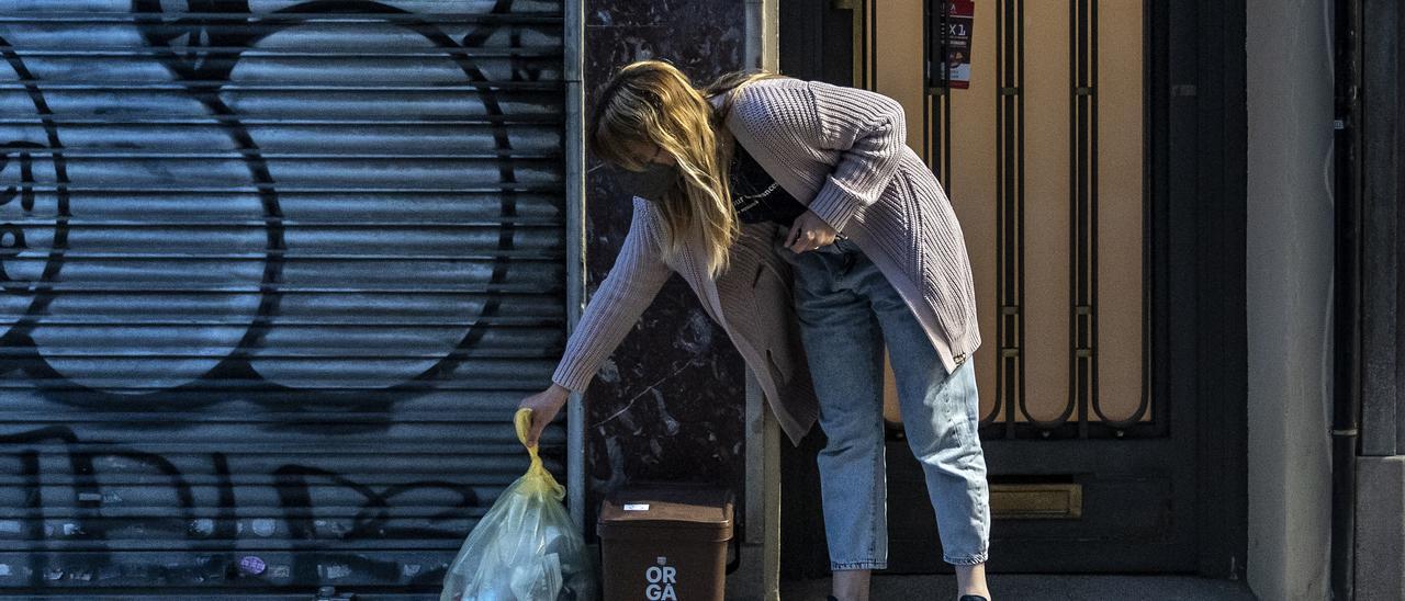 Una vecina de Sant Andreu deposita el cubo del orgánico y el plástico en el portal de su casa