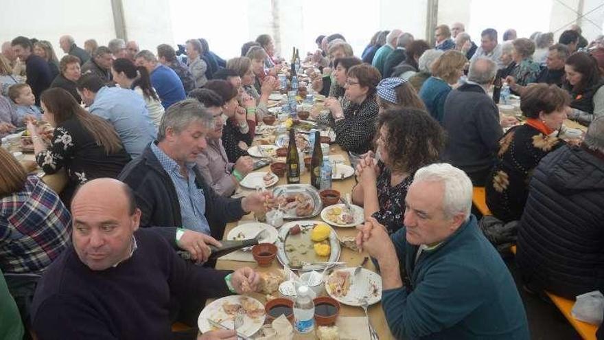 En la imagen superior, los cocineros preparan las raciones de lacón con grelos. Abajo, un aspecto de la carpa llena de gente. // Noé Parga