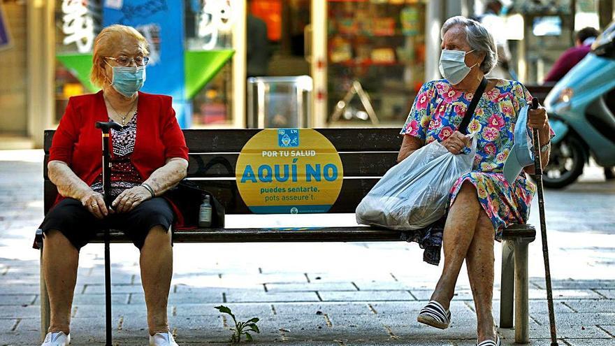 Dos mujeres con mascarilla conversan mientras guardan la distancia de seguridad, ayer en Barcelona.