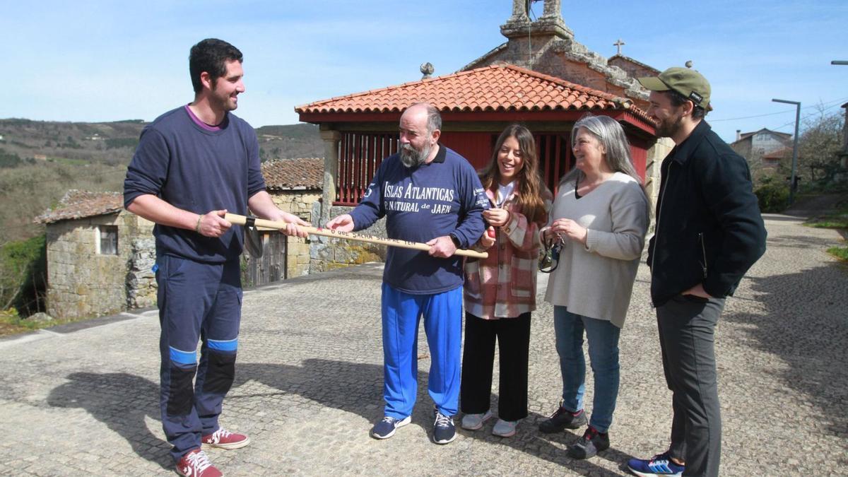 Conde (izquierda) muestra a los turistas, que este fin de semana se alojaron en la parroquia, el lema de su sacho