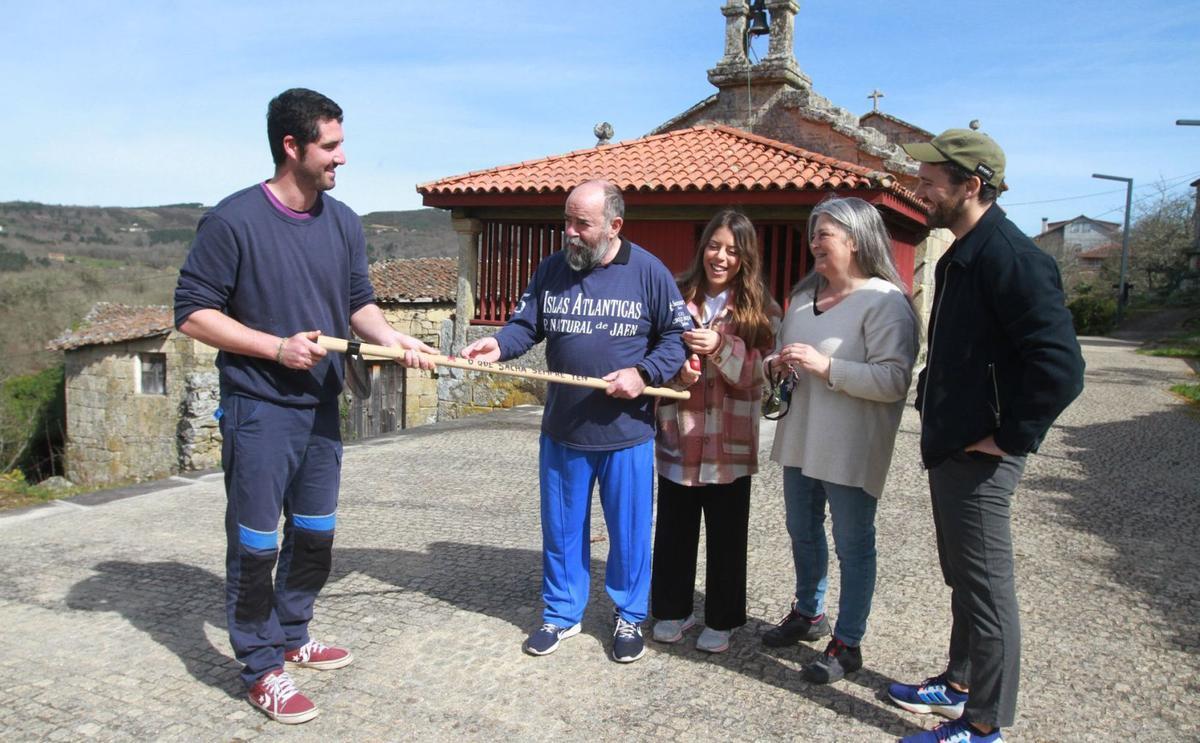 Conde (izquierda) muestra a los turistas, que este fin de semana se alojaron en la parroquia, el lema de su sacho