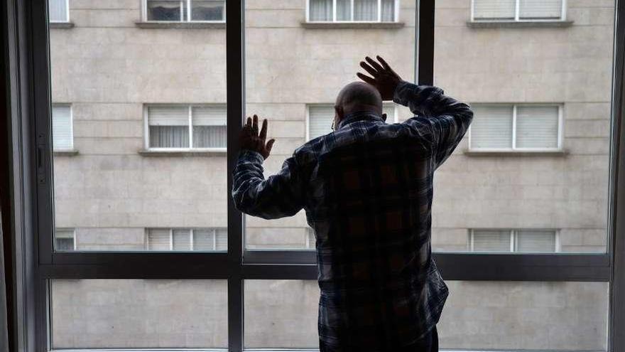 Una hombre mayor mira por la ventana del hogar en el que reside solo en Pontevedra. // Gustavo Santos