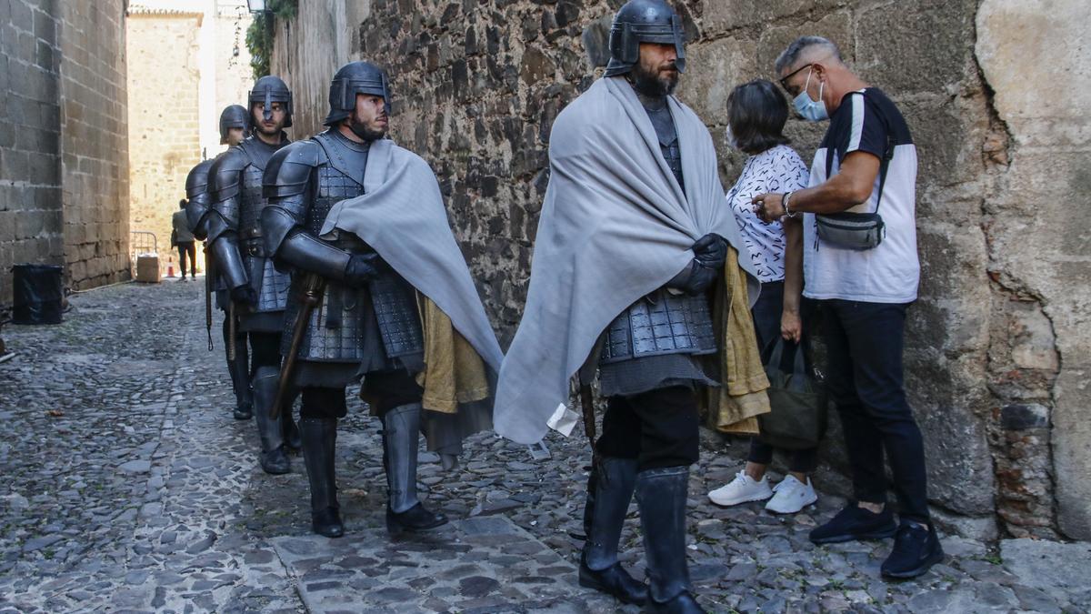 Rodaje Juego de Tronos. Unos extras pasan delante de turistas en la ciudad monumental cacereña en 2021.